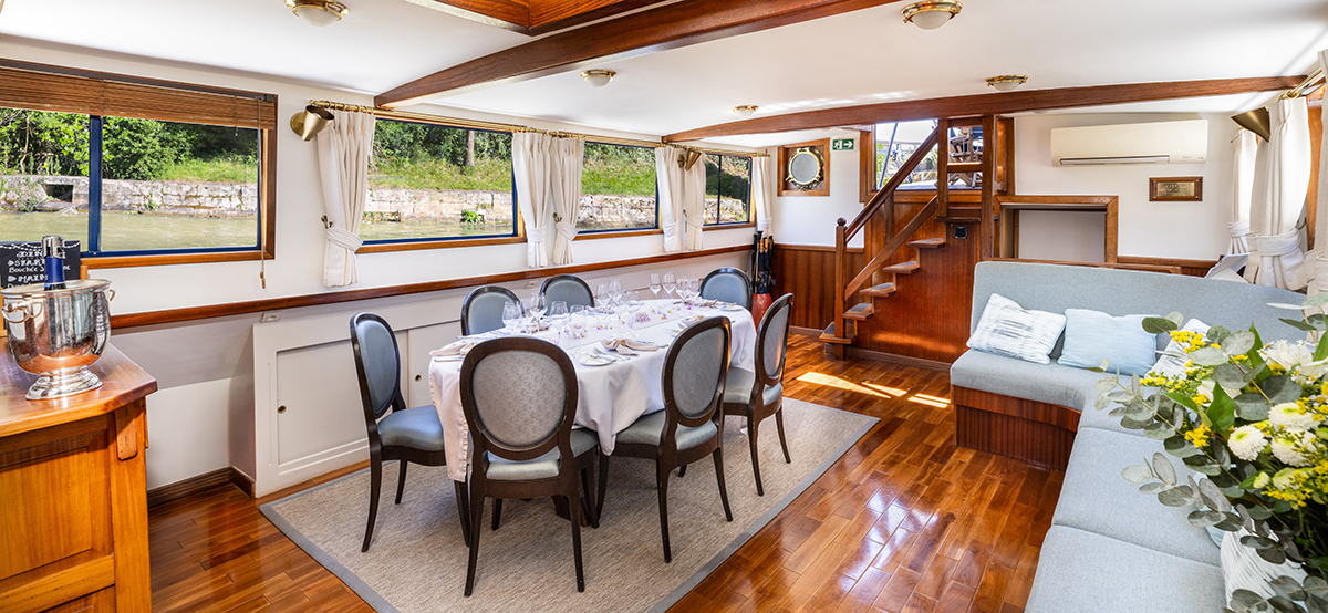 Spacious interior dining and lounge on board hotel barge Anjodi